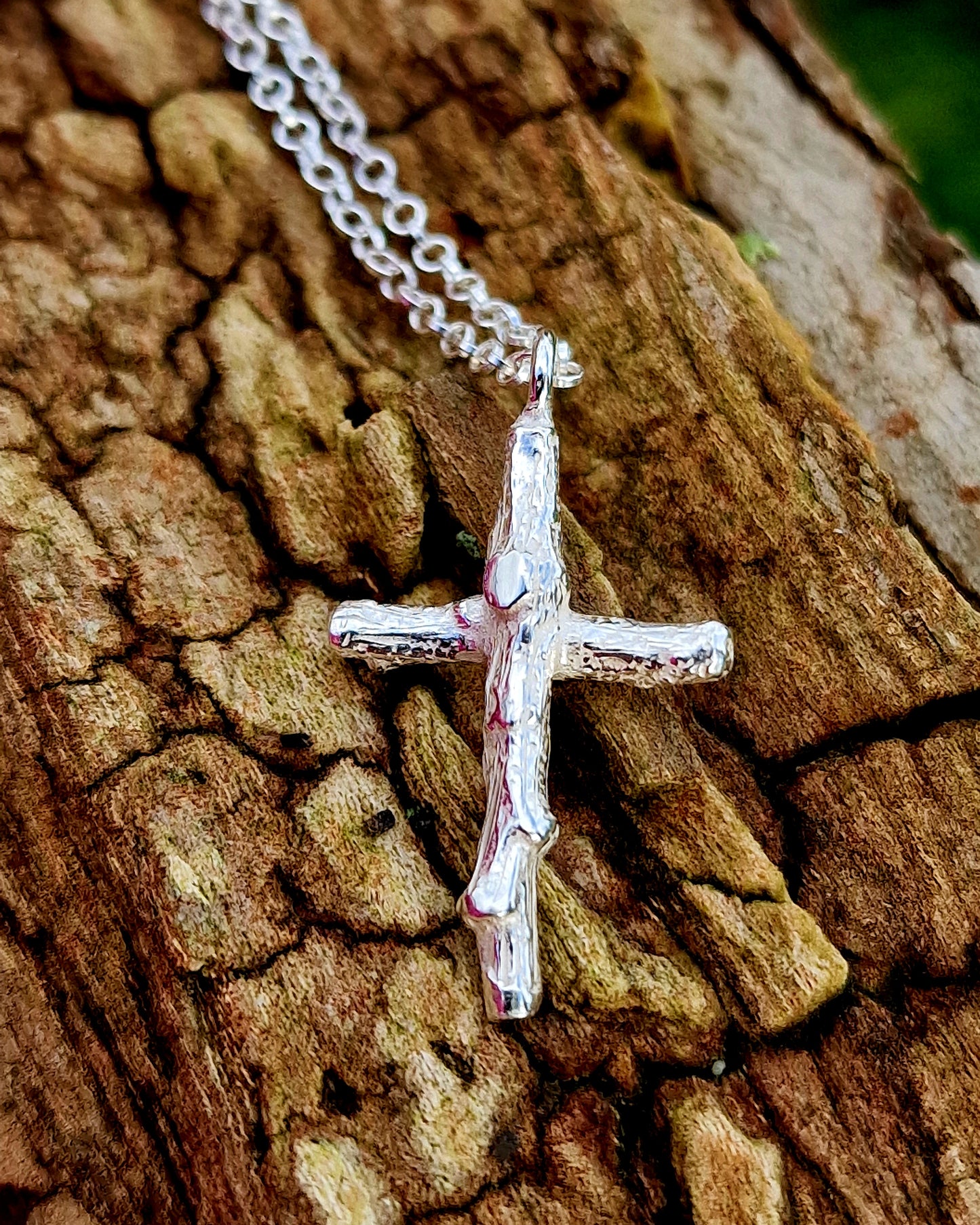 Handgefertigter Kreuzanhänger aus Silber, gestaltet aus zwei fein strukturierten Zweigen, die sich zu einem naturinspirierten Kreuz verbinden. Der Anhänger hängt an einer schlichten Silberkette und wirkt rustikal, symbolisch und elegant zugleich – perfekt als spiritueller Schmuck oder Geschenk für Naturliebhaber.